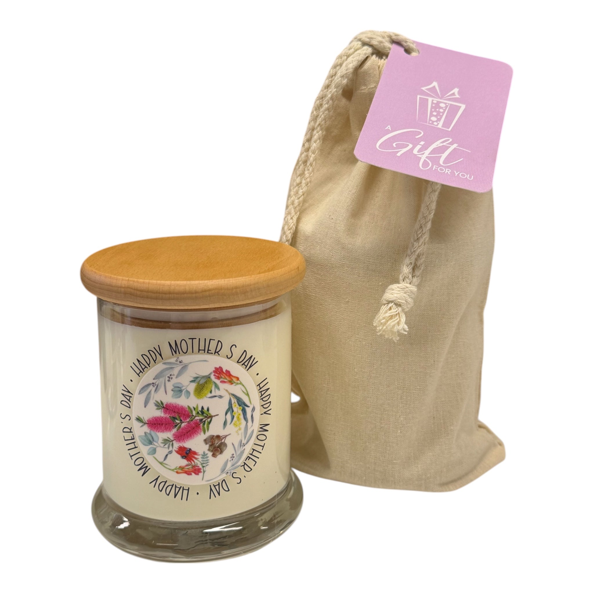 Glass candle with wooden lid and decorative label, accompanied by a beige drawstring bag with a pink tag.