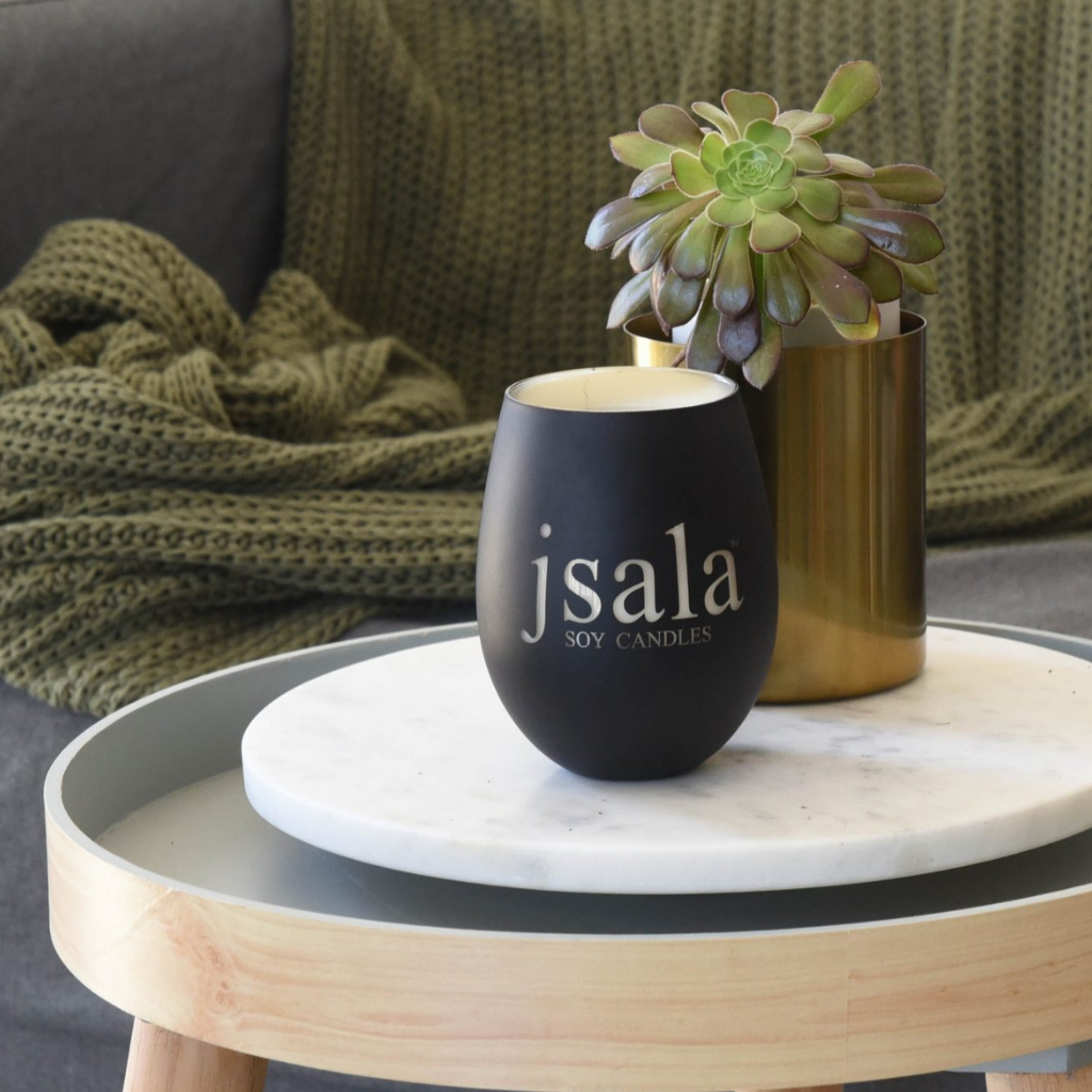 Black Illumination candle sitting next to succulent on marble platter on side table