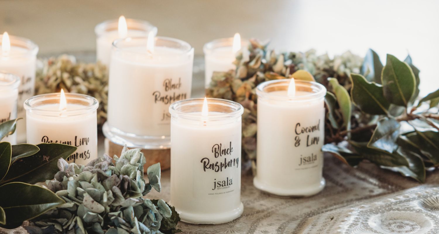 Collection of lit Jsala Apotecary candles surrounded by dried flowers and foliage.