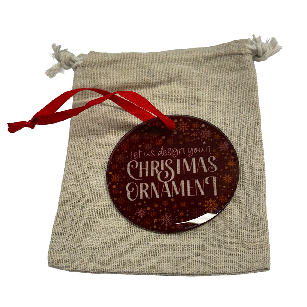 A Personalised round glass Christmas ornament with custom photo and message, red ribbon, and linen gift bag.