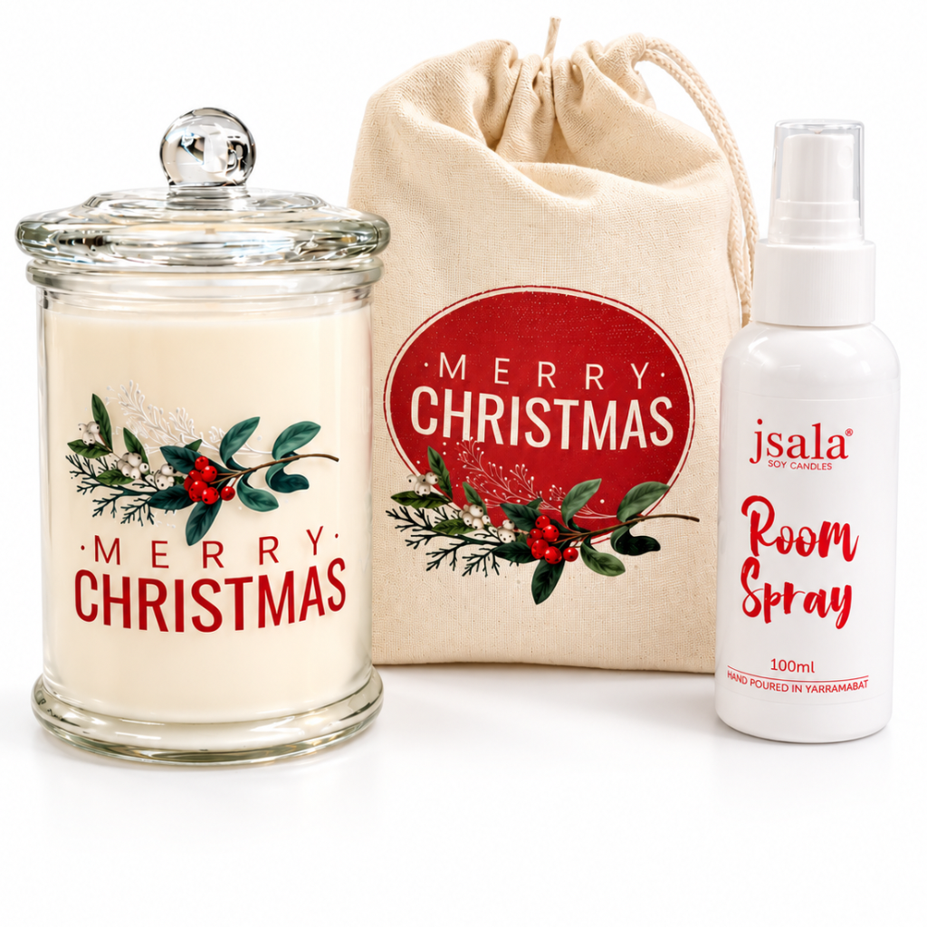 A Christmas-themed gift set featuring a glass jar candle with a 'Merry Christmas' label, a beige drawstring bag with a red 'Merry Christmas' logo, and a white room spray bottle labeled 'jsala Room Spray'.