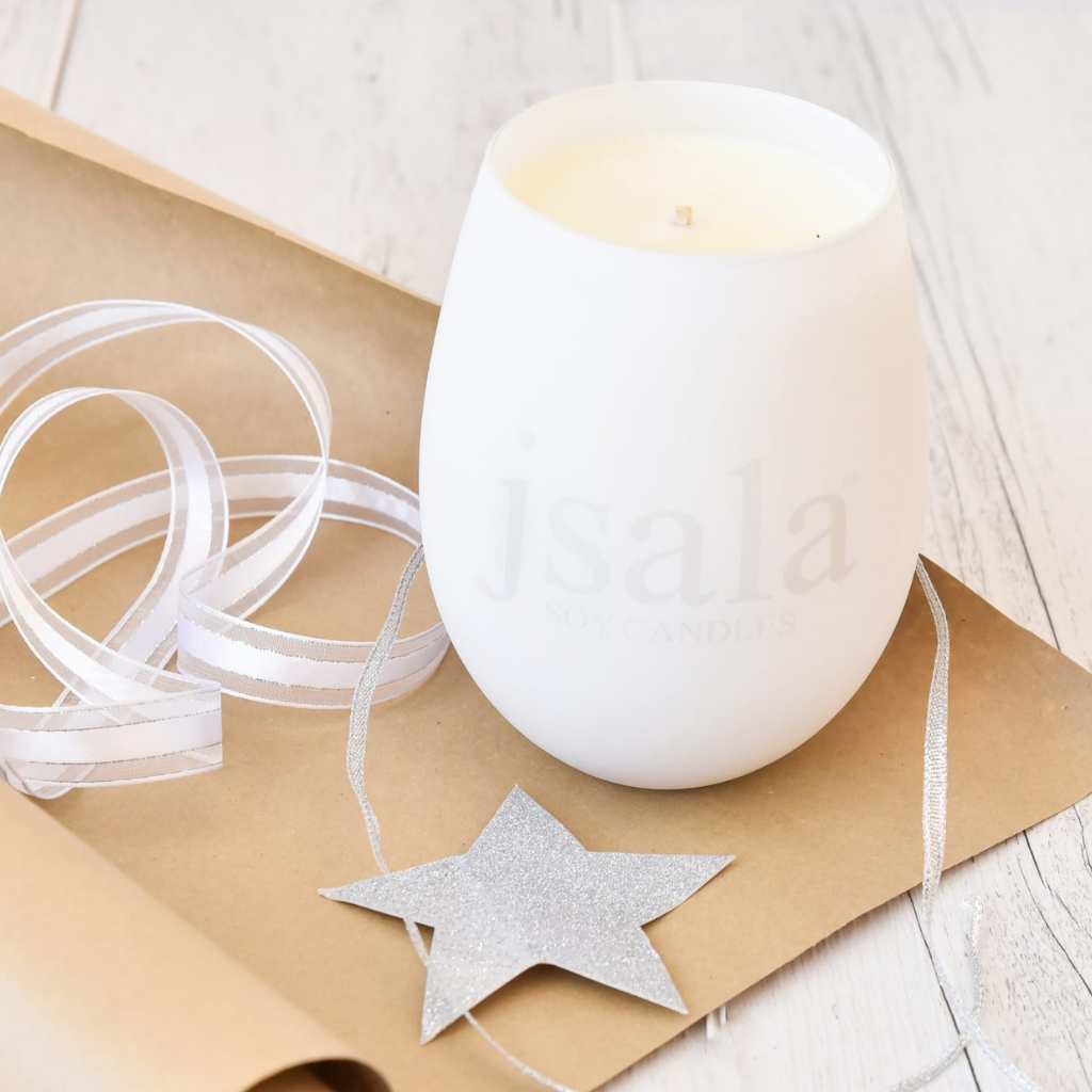 White Illumination Candle sitting on brown wrapping paper with ribbon